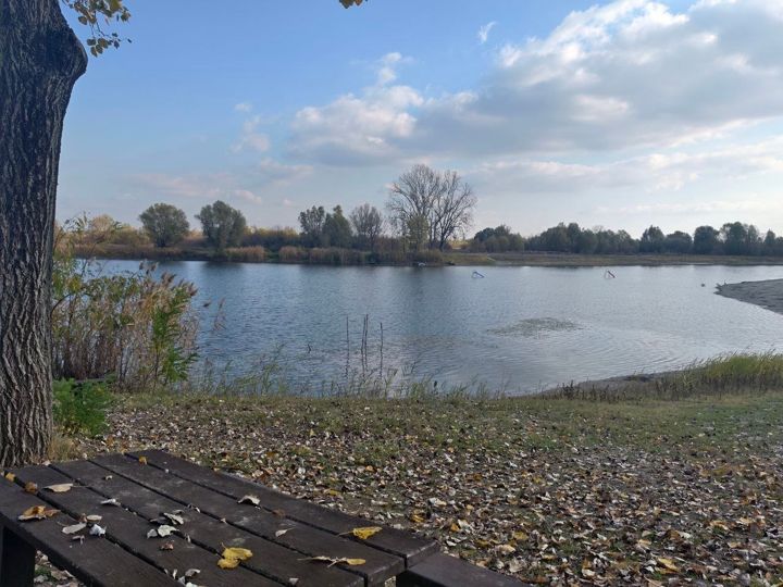 A wooden table under a poplar on the shore of Lake Provala in autumn, children's slides standing in the water